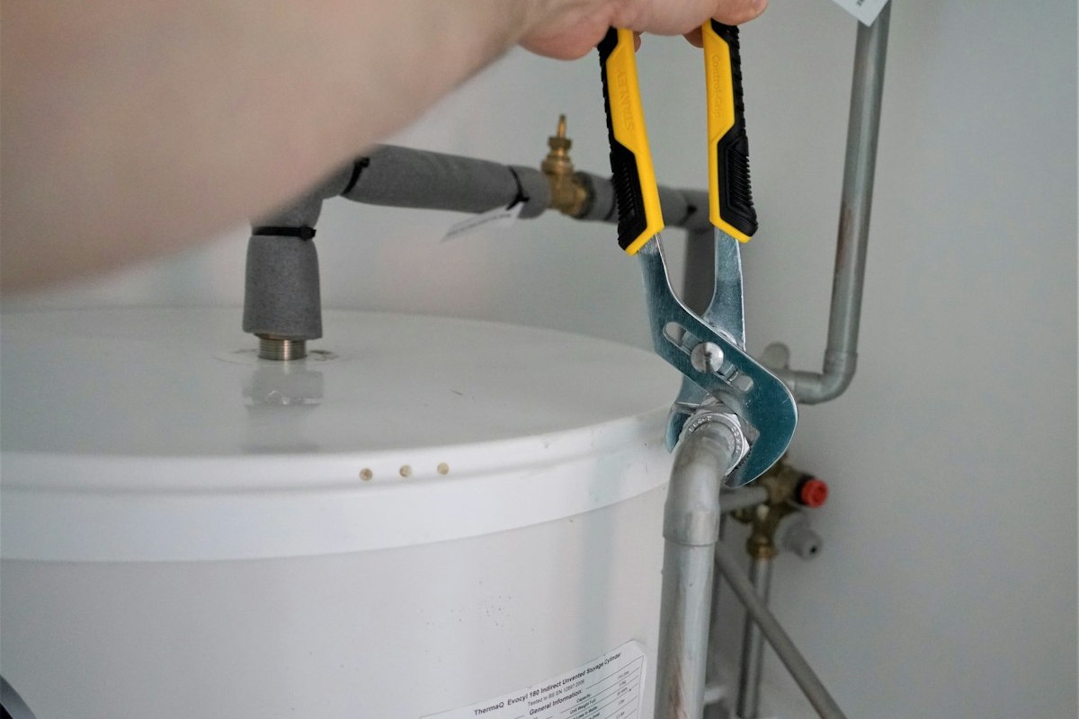 A plumber's hands working on a water line with a wrench